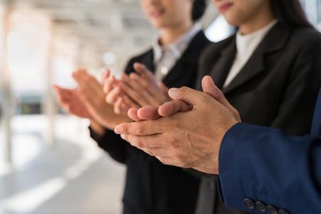 Three business people clap their hands to congratulate the signing of an agreement or contract between their firms, companies, enterprises. success, dealing, greeting and partner concept.の写真素材