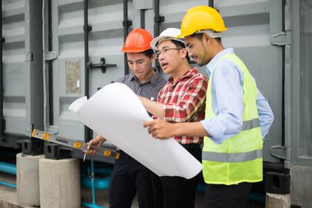 engineer and construction team wearing safety helmet and blueprint on hand. they are working on checking progress of construction site. engineer and client reviewing material and checking construction process in construction site area.の写真素材