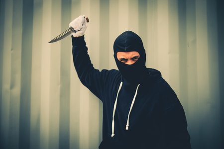 portrait of criminal or bandit wear black mask holding a knife and looking to camera, concept of cutthroat and assassinの写真素材