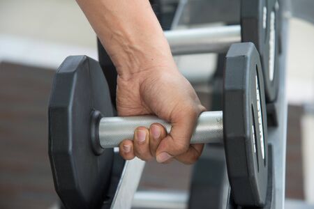 close up hand of sport man is holding dumbbell, exercising working out at the gym or fitness. ...