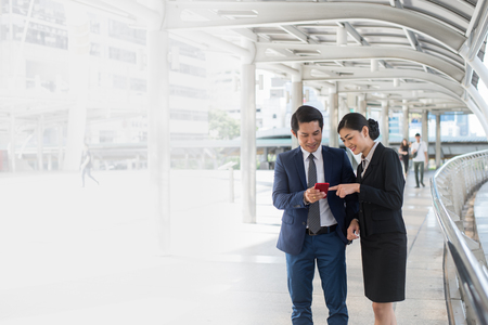 Asian businessman and businesswoman surf internet, shopping online and chat with friend on mobile phone.with copy space for textの写真素材