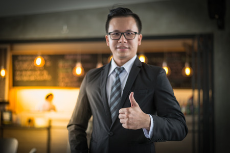 Asian businessman smile and show thumb up at the office. business successful conceptの写真素材