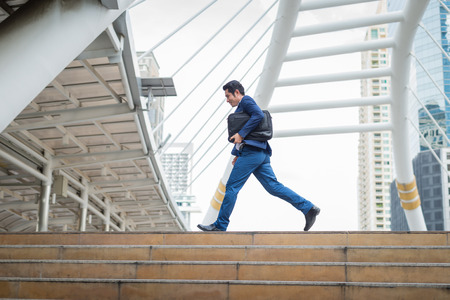 Businessman wear blue suit , he holding bag and running rapidly in the city. concept of rush hour and late for work.の写真素材