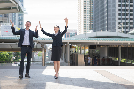 Asian businessman and businesswoman stand and raising up hands to celebrated his successful in career and mission. concept of winner and competition.の写真素材