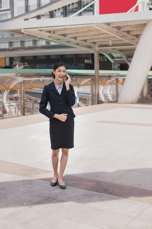 Asian business woman smile and hold cell phone to talk about business successの写真素材