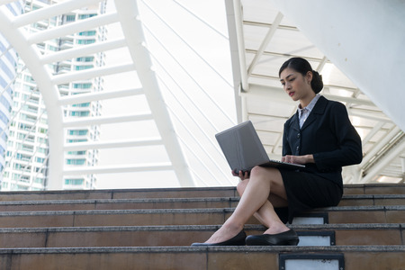 businesswomen sit on the staircase and typing word into laptopの写真素材