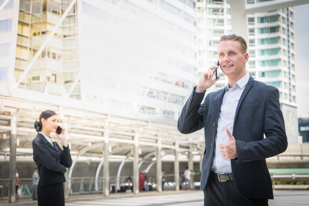 business man show thumb up and using mobile phone to talk about businessの写真素材