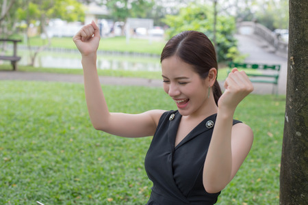 beautiful asian business woman smiling and raising up two hands to celebrate for business successful.の写真素材