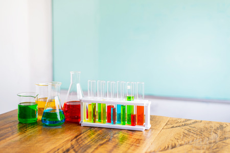 Multicolor chemical in glass test tube on plastic stand and beaker on wood table. with copy space for text.の写真素材