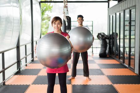 woman and man in sportswear, they are holding silver fitness ball. training conceptの写真素材
