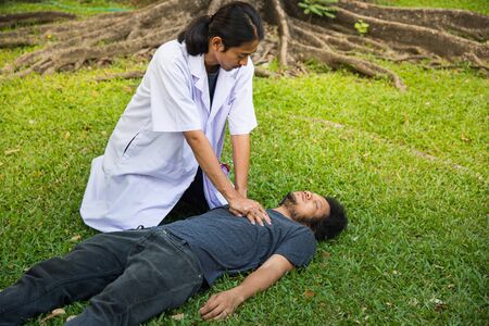 doctor help man by CPR, who heart attract and dead on green grass in the garden