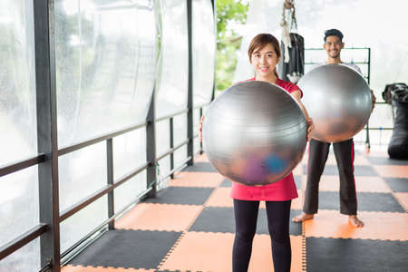 sportswoman and sportsman in sportswear, they are holding silver fitness ball for exercise. training conceptの写真素材
