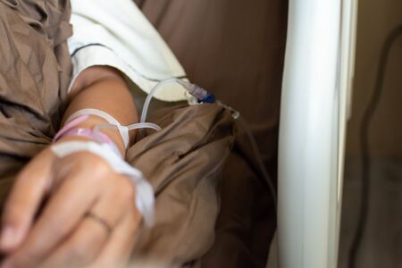 The young woman, lying on the bed with an arm, sent a solution of saline solution to the hospital for treatment at the hospital.の写真素材