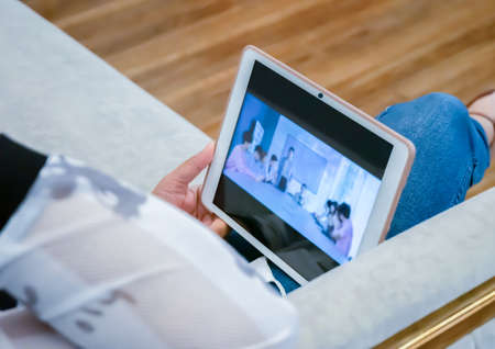 The young woman sat and watched the teleconference through the tablet.