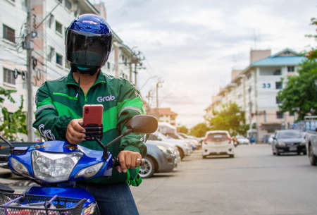 The food delivery driver uses a mobile phone to check the route to deliver products to customers who...