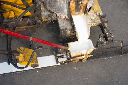 The machines are pouring white paint over the road to divide the lines on the road.の写真素材