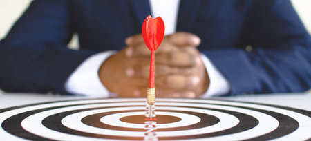 A dart sheet with darts placed in the center, placed in front of a businessman, concept of business objectives for successの写真素材
