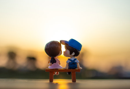 A couple dolls sitting on a bench watching the evening sunset Valentine day concept