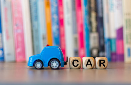 Cars letters on a wooden cube and a blue toy car.