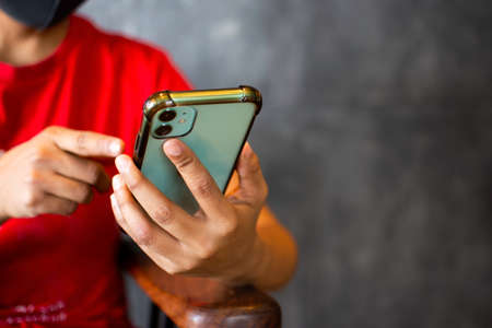 Back holding a smartphone in the hand of a young woman at a restaurant The concept of social network...