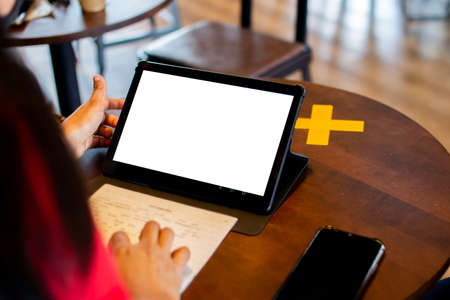 A blank white tablet screen for text input or exiting. Model on a brown wooden table in a coffee...