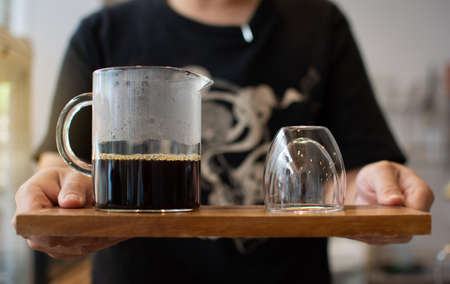 Drip coffee in a glass on a wooden tray ready to be served in a coffee shop.