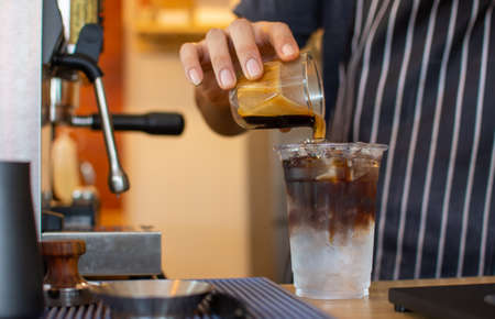 The ballista pours iced American coffee into a cup in the coffee shop to prepare and serve it to customers.の写真素材