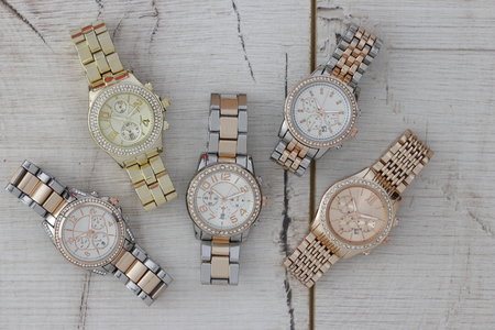 Metal watches for women placed on a wooden surface