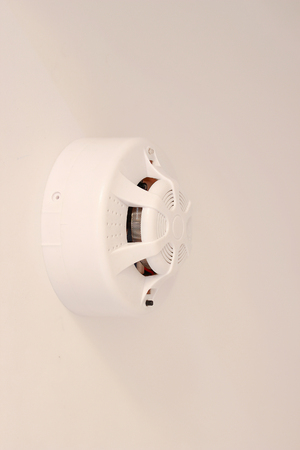 A white smoke detector on white ceiling