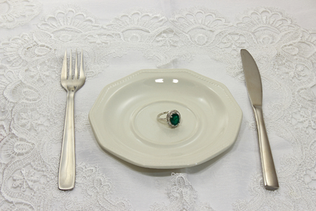 Silver ring with emerald put on a white plateの写真素材