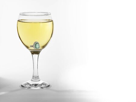 Gass with wine and engagement ring on white backgroundの写真素材