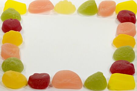 Colorful fruit candies arranged in the shape of snake on a white backgroundの写真素材