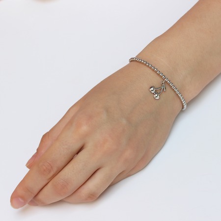 A woman's hand with silver bracelet with a lucky charmの写真素材