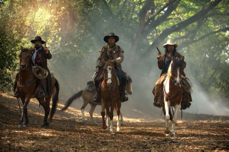 Cowboy riding a horse carrying a gunの写真素材