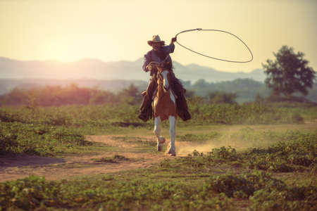 Cowboy riding a horse carrying a gunの写真素材
