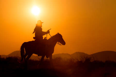 Cowboy silhouette riding a horse When the sunset looks beautifulの写真素材
