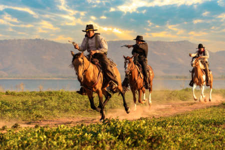 Cowboy riding a horse carrying a gunの写真素材
