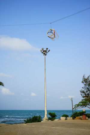 Tri-color sepak takraw hoop hanging by the seaの写真素材