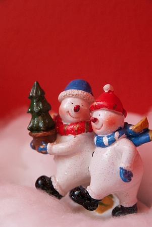 Miniature of two snow man walking forward while holding a Christmas tree.の写真素材