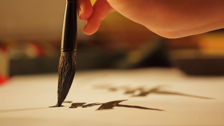 Close up on hand holding brush writing calligraphyの写真素材