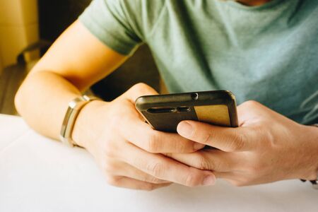 Close up on the hands of a young handsome man using a smartphone