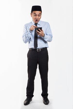 Asian male with songkok looking at his phoneの写真素材