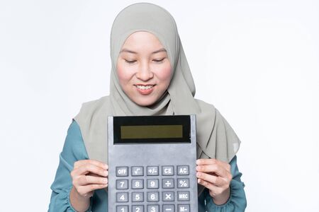 Female muslim holding a big calculator with facial expression - financial concept.の写真素材
