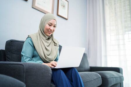 Female muslim using laptop at home environment.の写真素材