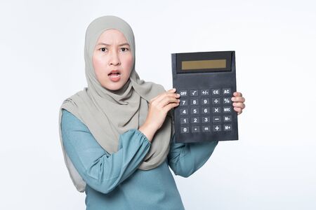 Female muslim holding a big calculator with facial expression - financial concept.の写真素材