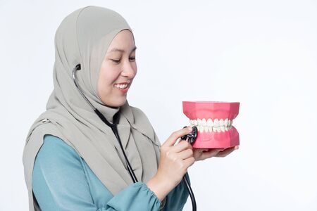 Muslim woman holding a stethoscope while inspecting a dental mould.の写真素材