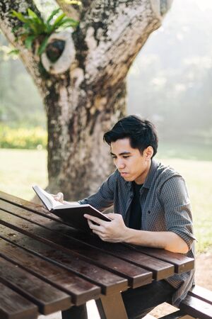 Young man studying alone at a parkの写真素材