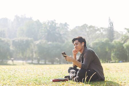 Young man selecting and listen to music using his deviceの写真素材