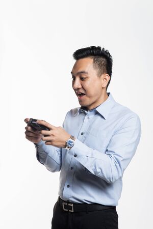 Asian man in work cloth playing console gameの写真素材
