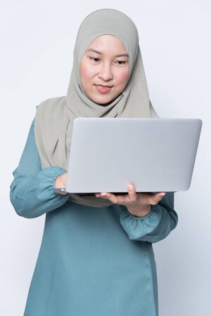 Muslim woman using a laptop with facial expression.の写真素材